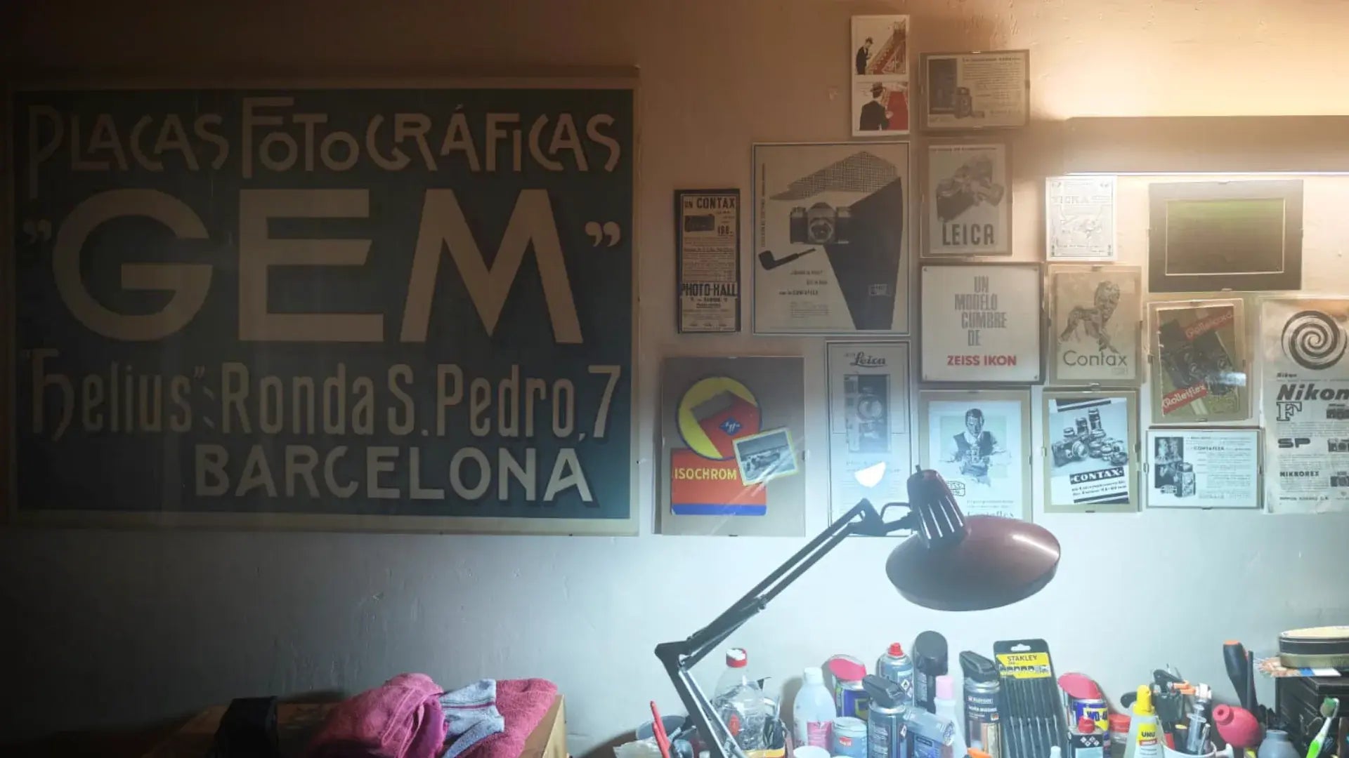 Mesa de trabajo con cámaras analógicas y carteles antiguos de fotografía